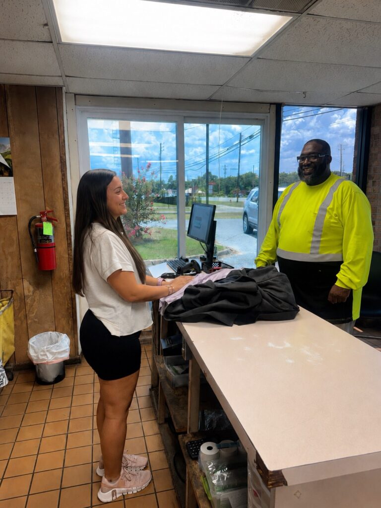 A Waite's Cleaners team member taking in garments from a customer at the counter